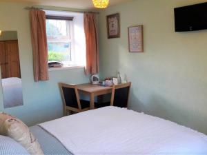 a bedroom with a bed and a table and a window at Hazels Roost in Bainbridge