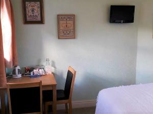 a room with a desk and a bed and a desk and a table and chair at Hazels Roost in Bainbridge +7 photos