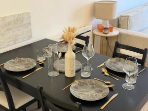 a table with plates and glasses and a bottle of wine at La Parenthèse Mézoise – Port plage à pied in Mèze +9 photos