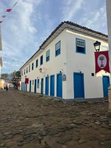 a white building with blue doors and a flag at Pousada santa rita in Paraty