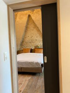 a bedroom with a bed and a stone wall at Studio Mad Grace in Diksmuide +4 photos
