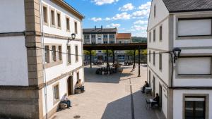 a group of people sitting in a courtyard between two buildings at Pensión 813 in Palas de Rei