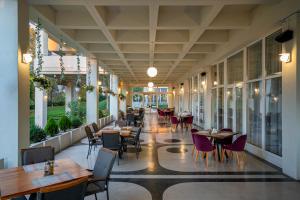 a restaurant with tables and chairs and windows at Hotel Belvedere in Cluj-Napoca