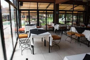 a restaurant with white tables and chairs and windows at Hotel Samka in Salta