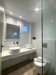 a white bathroom with a sink and a toilet at Kostas Apartments in Stalís