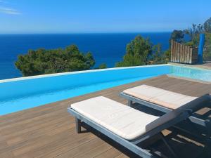a pool with two lounge chairs and the ocean at Villa Luxury Paradise Suites in Salobreña