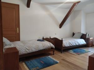 a bedroom with two beds and a door with rugs at Grès Vaillant in Saint-Polycarpe