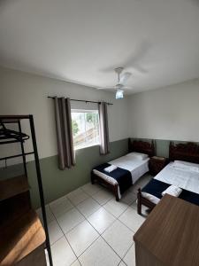 a bedroom with two beds and a window at Aconchegante Apartamento in Lavras