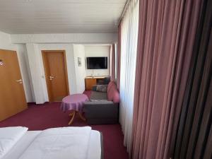 a hotel room with a couch and a tv at Hotel am Neckar in Nürtingen