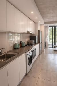 a white kitchen with a sink and a dishwasher at Luxury Coastal Escape Coral Point Sibaya Pool & WiFi in Durban