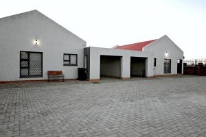 a white building with a bench in a courtyard at On 47a in Kimberley