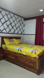 a wooden bed with a yellow comforter and flowers on it at Résidence meublée du boss in Abidjan