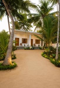 a white house with palm trees and a driveway at One FS Hotel Arugambay in Arugam Bay