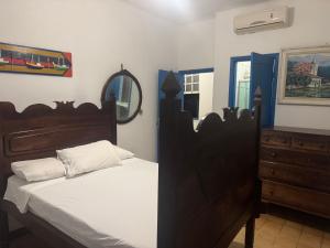 a bedroom with a bed and a dresser and a mirror at Pousada santa rita in Paraty
