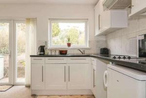 a white kitchen with a sink and a window at Bungalow - Sleeps 2 - Parking in Newquay +11 photos