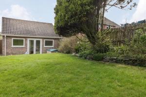 a house with a green yard with a tree at Bungalow - Sleeps 2 - Parking in Newquay