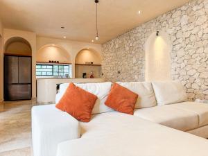 ein Wohnzimmer mit weißem Sofa und Steinwand in der Unterkunft Casa Bacah in Bacalar