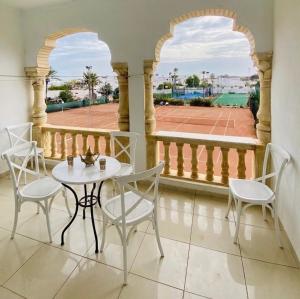 a balcony with a table and chairs and a tennis court at Le palmier in Mezraya
