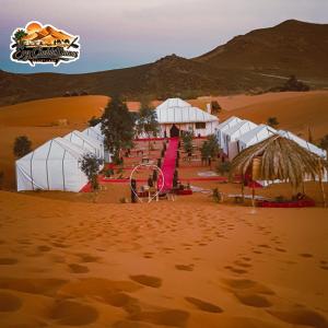 a desert with white tents in the sand at Erg Chebbi Dunes Desert Camp in Merzouga