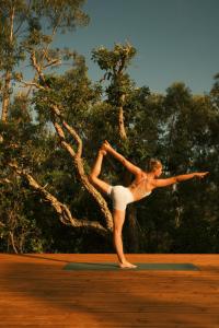 a woman is standing on a mat with her leg up at Helder Farm Studios in São Teotónio