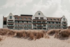 a building on the beach with sand dunes in front of it at Hotel de Blanke Top in Cadzand-Bad