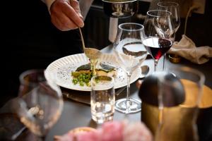 a person eating a plate of food on a table with wine glasses at Westergaards Hotel in Videbæk +23 photos