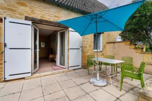 a blue umbrella on a patio with a table and chairs at Gite Echo in Salignac Eyvigues