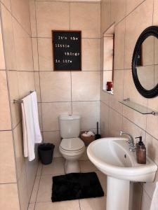 a bathroom with a white toilet and a sink at Cottage Hill in Gqeberha