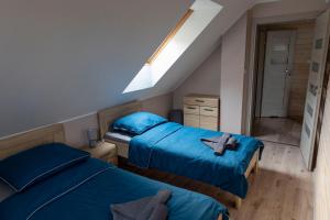 two beds in a small room with blue sheets at Leśna Przystań in Sasino