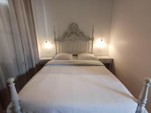 a white bed in a bedroom with two lamps at Au Thiernois in Thiers