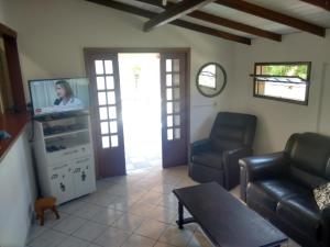ein Wohnzimmer mit Sofa und Fernseher in der Unterkunft Casa Dunas in Florianópolis