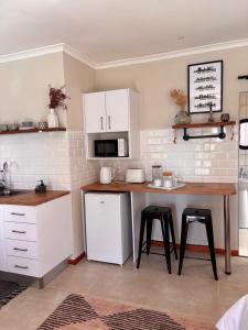 a kitchen with white cabinets and a table and stools at Cottage Hill in Gqeberha