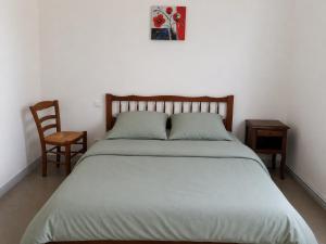 a bedroom with a large bed and a chair at La Parenthèse du Lot in Gramat