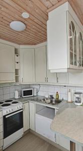 a kitchen with white appliances and a wooden ceiling at Sorvarinraitin Helmi in Seinäjoki
