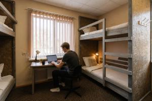 a man sitting at a desk in a room with bunk beds at Hang The Hat House in Valmiera