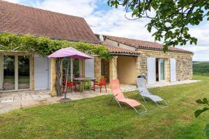 a house with a table and chairs and an umbrella at Gite Four De Mon Père in Salignac Eyvigues
