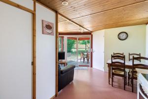a living room and dining room with a clock on the wall at Chalet Le Tilleul in Salignac Eyvigues