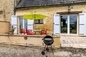 a grill with two chairs and a table with an umbrella at Gîte Charly in Salignac Eyvigues