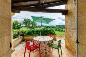 a table and chairs with a green umbrella on a patio at Gite Sierra in Salignac Eyvigues