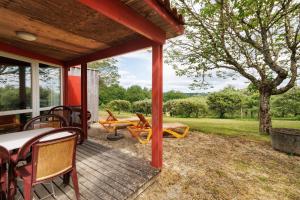 a porch with a table and chairs and a tree at Chalet Le Tilleul in Salignac Eyvigues