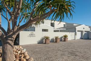 a tree in front of a white building at Spatalla Holiday Homes in Kleinmond +24 photos
