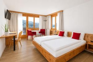 a bedroom with a large bed with red pillows at Hotel Seehof direkt am Heidsee in Valbella +57 photos