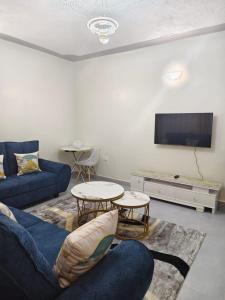 a living room with a blue couch and two tables at GLOW Suites in Naivasha