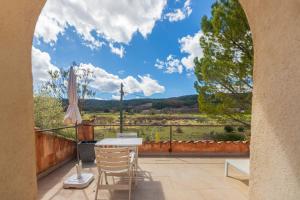 a patio with a table and chairs on a balcony at La Ferme Rose-Hôtel de Charme in Moustiers-Sainte-Marie