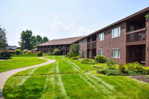 a house with a green lawn next to a building at Fireside Inn & Suites Gilford in Gilford