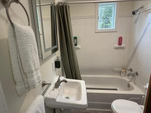 a white bathroom with a sink and a tub at Woodford Rest in Woodford +15 photos