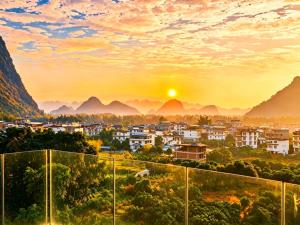 eine Stadt in den Bergen bei Sonnenuntergang in der Unterkunft THAT MAY Hotel in Yangshuo