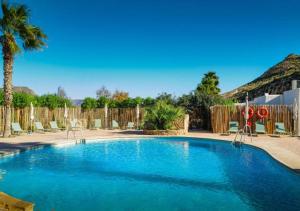 a swimming pool with chairs and a fence at wecamp Cabo de Gata in Las Negras
