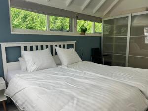 a bedroom with a large white bed with white pillows at De Zeebries in Warmenhuizen