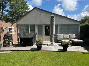 a patio with a couch and a table and a grill at De Zeebries in Warmenhuizen